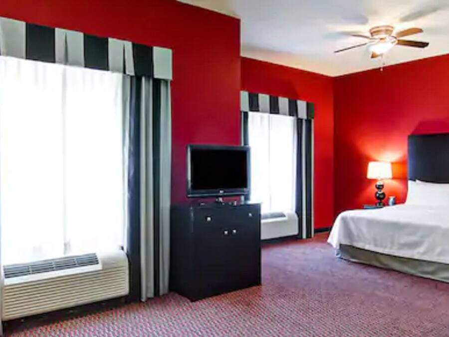 A hotel room with a bed, a desk, a television, and a ceiling fan.