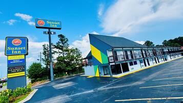 A motel with a blue and yellow exterior, a flat-screen TV in each room, and a sign indicating it is under new management.