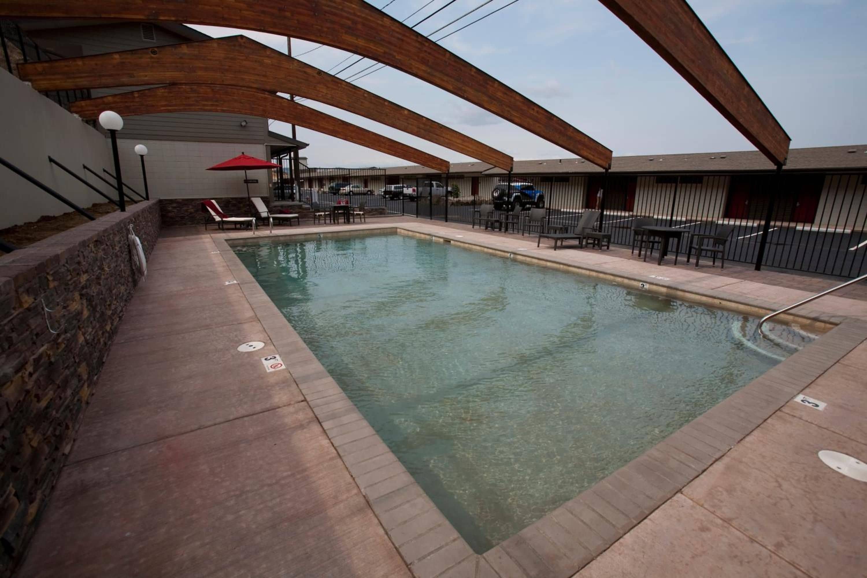 Una piscina con un muro de piedra en un lado y una zona techada con asientos en el otro.