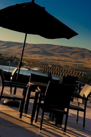 Outdoor seating with a view of a dam and hills.