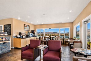 A restaurant with a kitchen, seating area, and large windows offering a view of the landscape.