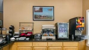 A breakfast bar with a coffee machine, toaster, and refrigerated display. - Celilo Inn (The Dalles)