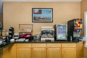 A breakfast bar with a coffee machine, toaster, and refrigerated display.