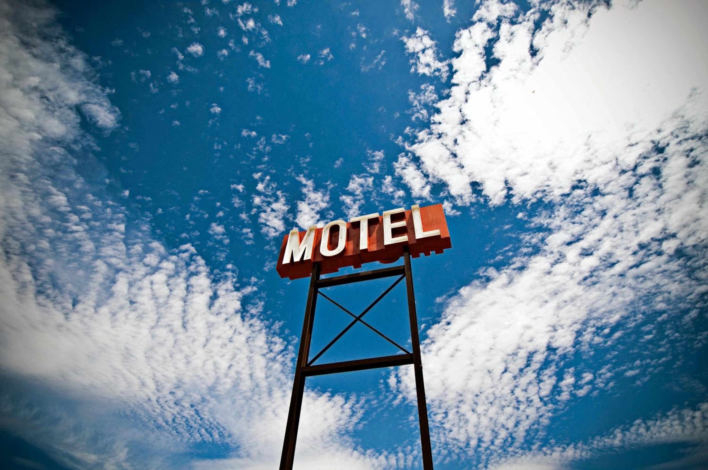 A motel sign against a sky with clouds.