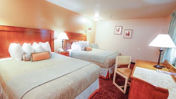 Habitación de hotel con dos camas, un escritorio, una silla y una lámpara.