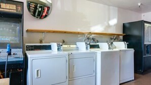 A laundry room with four front-loading washing machines, a dryer, and a vending machine. - Heritage Inn La Mesa (La Mesa)