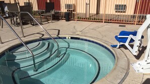A swimming pool with a metal ladder, a blue chair, and a white chair. - Heritage Inn La Mesa (La Mesa)