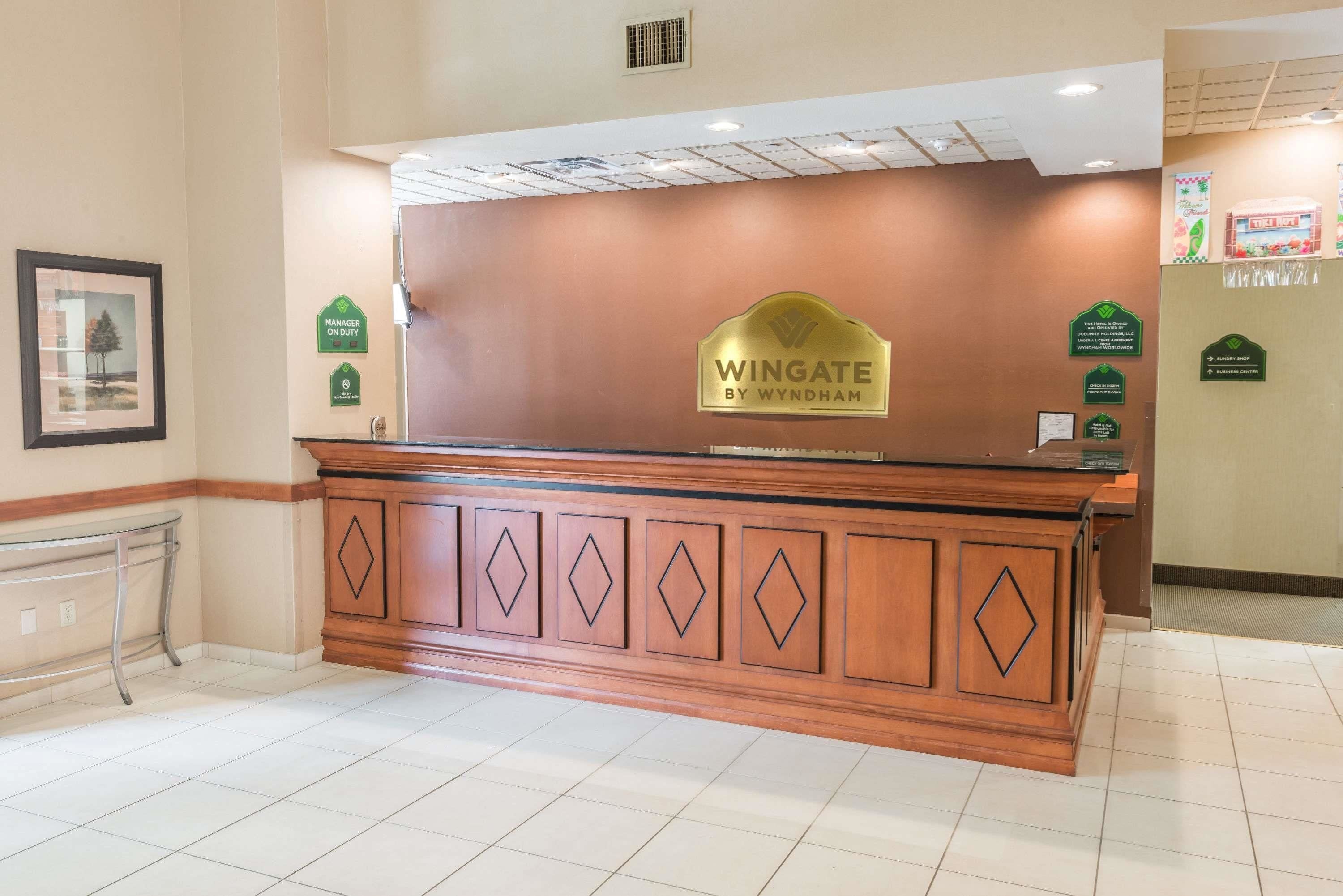 A reception desk with a sign reading "Wingate by Wyndham" and a framed picture on the wall.