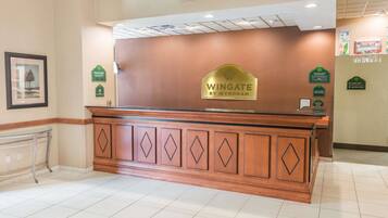 A reception desk with a sign reading "Wingate by Wyndham" and a framed picture on the wall.