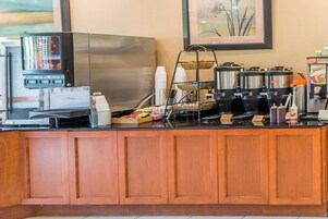 Una estación de café con una máquina de café, un dispensador de bebidas y un carrito de café.