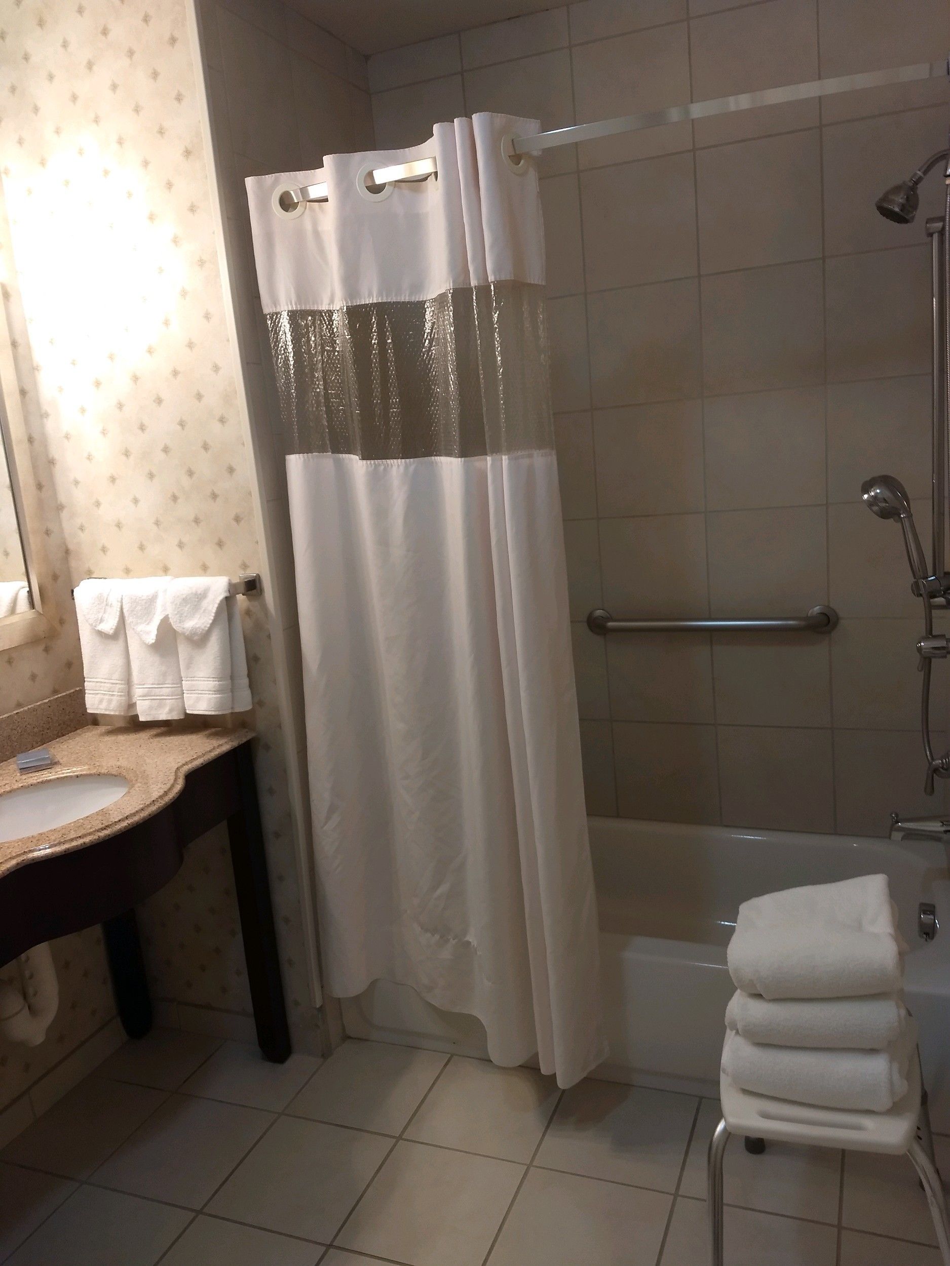 A bathroom with a bathtub, a shower curtain, a sink, and a towel rack.