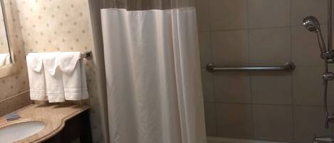 A bathroom with a bathtub, a shower curtain, a sink, and a towel rack.