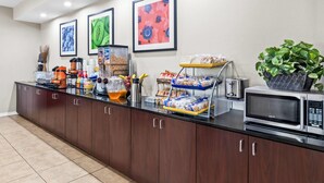 Una zona de cocina con microondas, cafetera y diversos alimentos sobre la encimera.