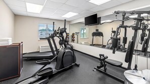 Un gimnasio con cintas de correr, elípticas y equipo de levantamiento de pesas.