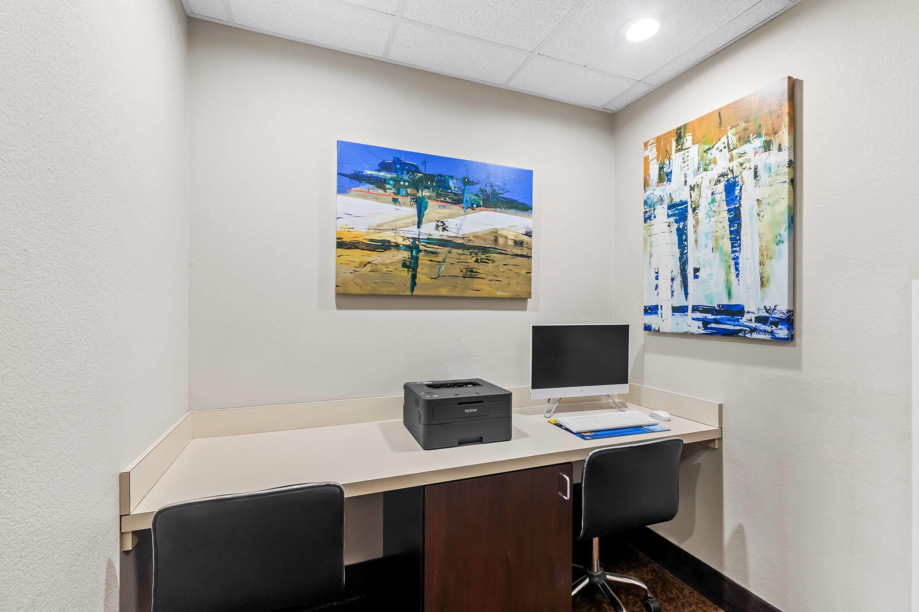 A modern office space with a desk, two chairs, a printer, and two paintings on the wall.