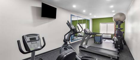 Un gimnasio con cintas de correr, elípticas y bicicletas estáticas.
