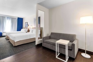 A hotel room with a bed, a sofa, a small table, and a floor lamp. - Spark by Hilton Pearland (Pearland)
