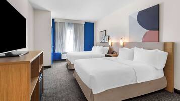 Ein Hotelzimmer mit zwei Betten, einem Schreibtisch, einem Fernseher und einem großen, abstrakten Gemälde an der Wand.