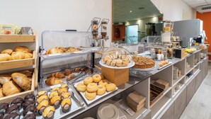 A breakfast buffet with various pastries, including croissants and donuts, and a coffee machine. - Hotel Italia (Trieste)