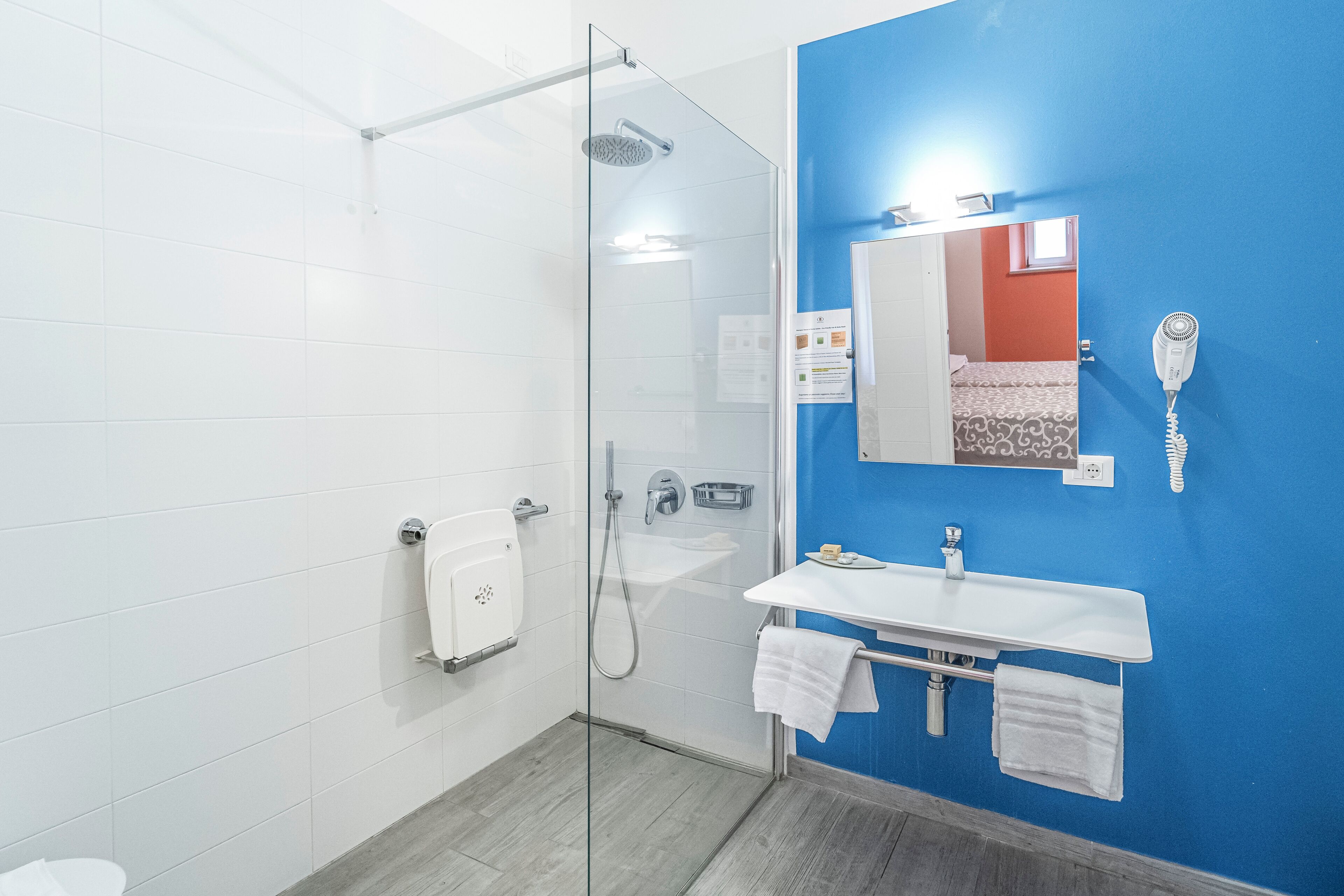 Un baño moderno con cabina de ducha de vidrio, lavamanos blanco y pared decorativa azul.
