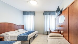 A hotel room with two single beds, a desk with a chair, a mirror, and a TV on the wall. - Hotel Italia (Trieste)