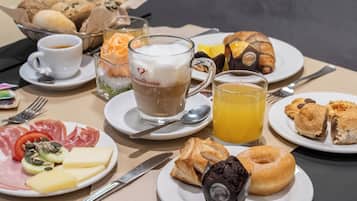 A breakfast setting with various food items and beverages on plates and in cups.