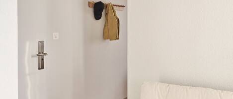 Una habitación moderna y minimalista con piso de madera, una puerta blanca y una cama con dos almohadas.