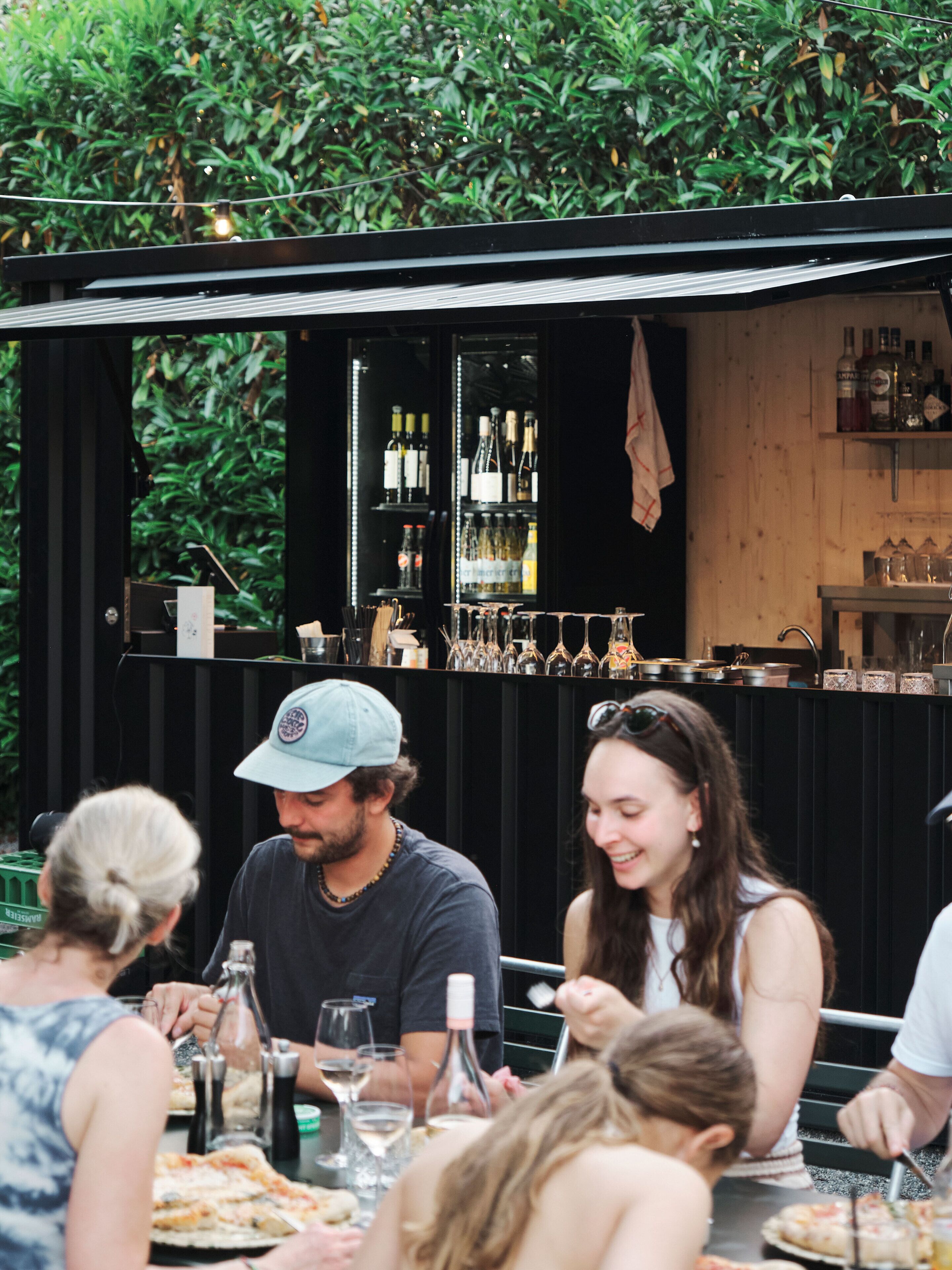Un espace extérieur aménagé pour prendre les repas, avec un bar en arrière-plan.