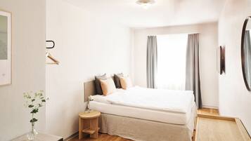 Una camera da letto moderna con un letto grande, un comodino, uno sgabello, un quadro incorniciato e uno specchio appeso al muro.