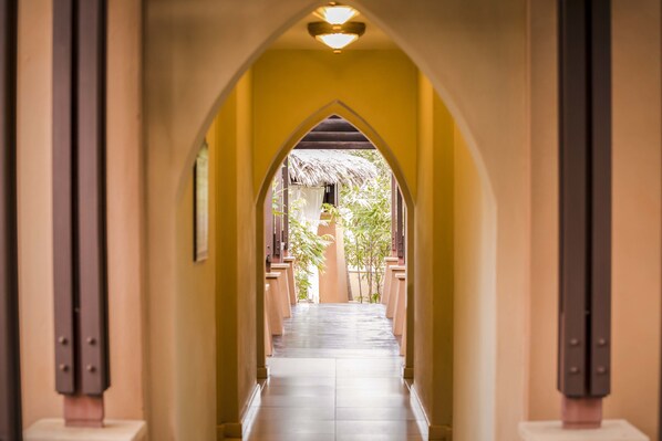 A corridor with a vaulted ceiling and a thatched roof visible through an archway. - Avani Pemba Beach Hotel (Pemba)