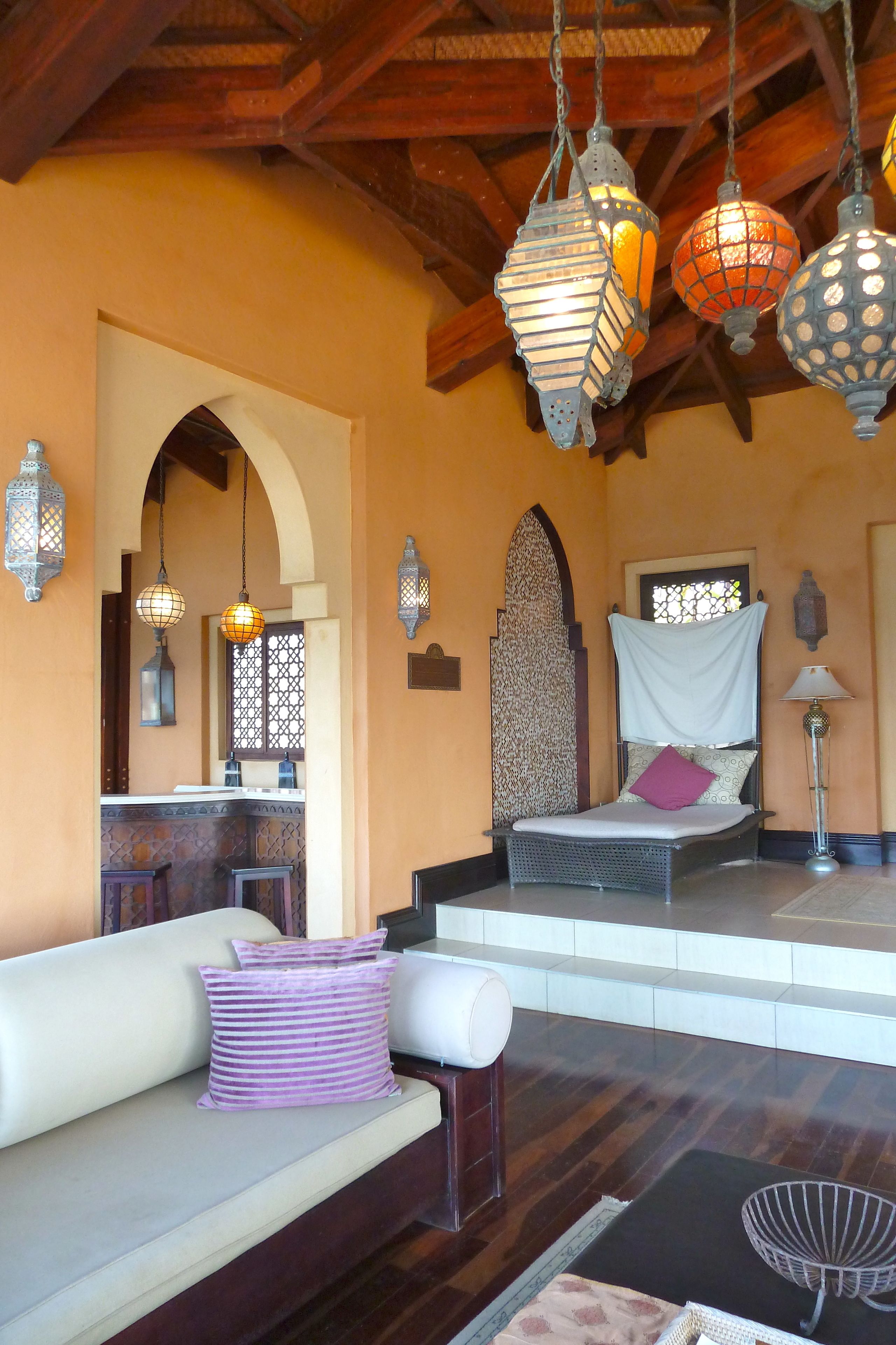 A cozy room with a bed, a sofa, and hanging lanterns.