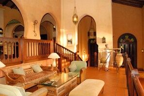 A spacious lobby with a wooden staircase, comfortable seating, and a large vase. - Avani Pemba Beach Hotel (Pemba)