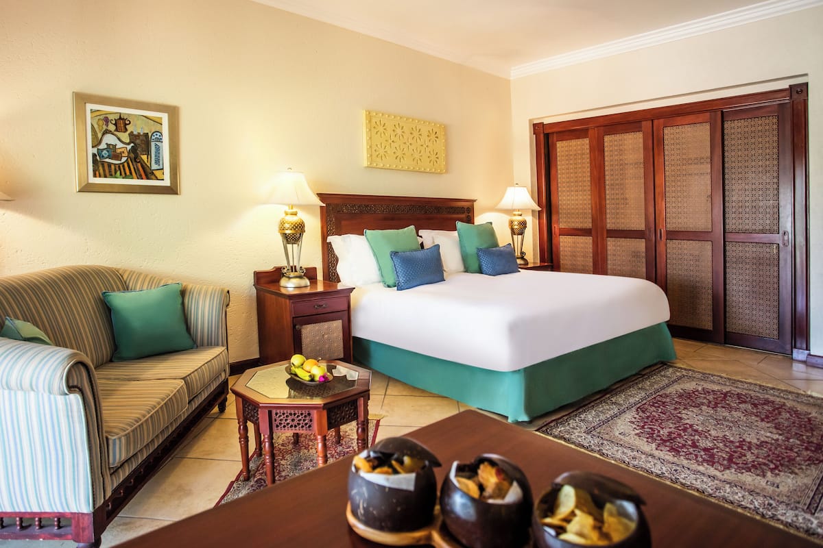 Una habitación de hotel con cama, sof á, una pequeña mesa con fruta y una lámpara decorativa.