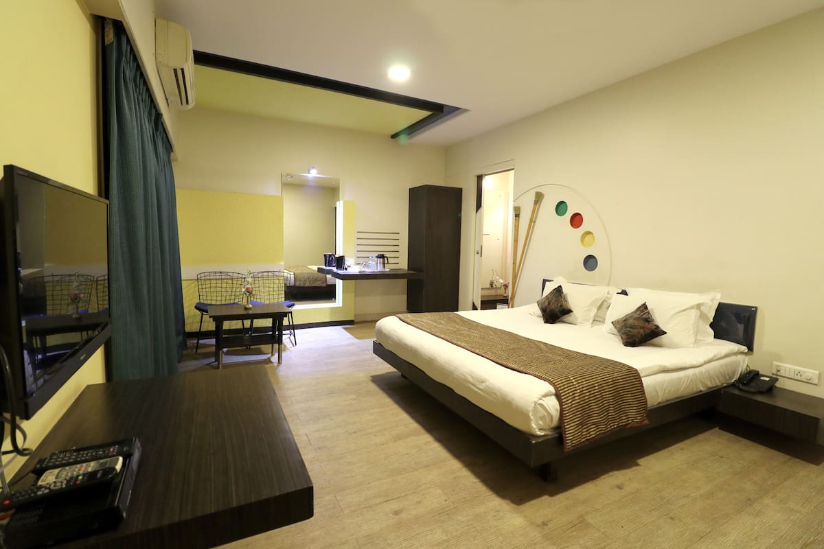 Ein Hotelzimmer mit einem großen Bett, einem Fernseher, einem Schreibtisch und einem Sessel.