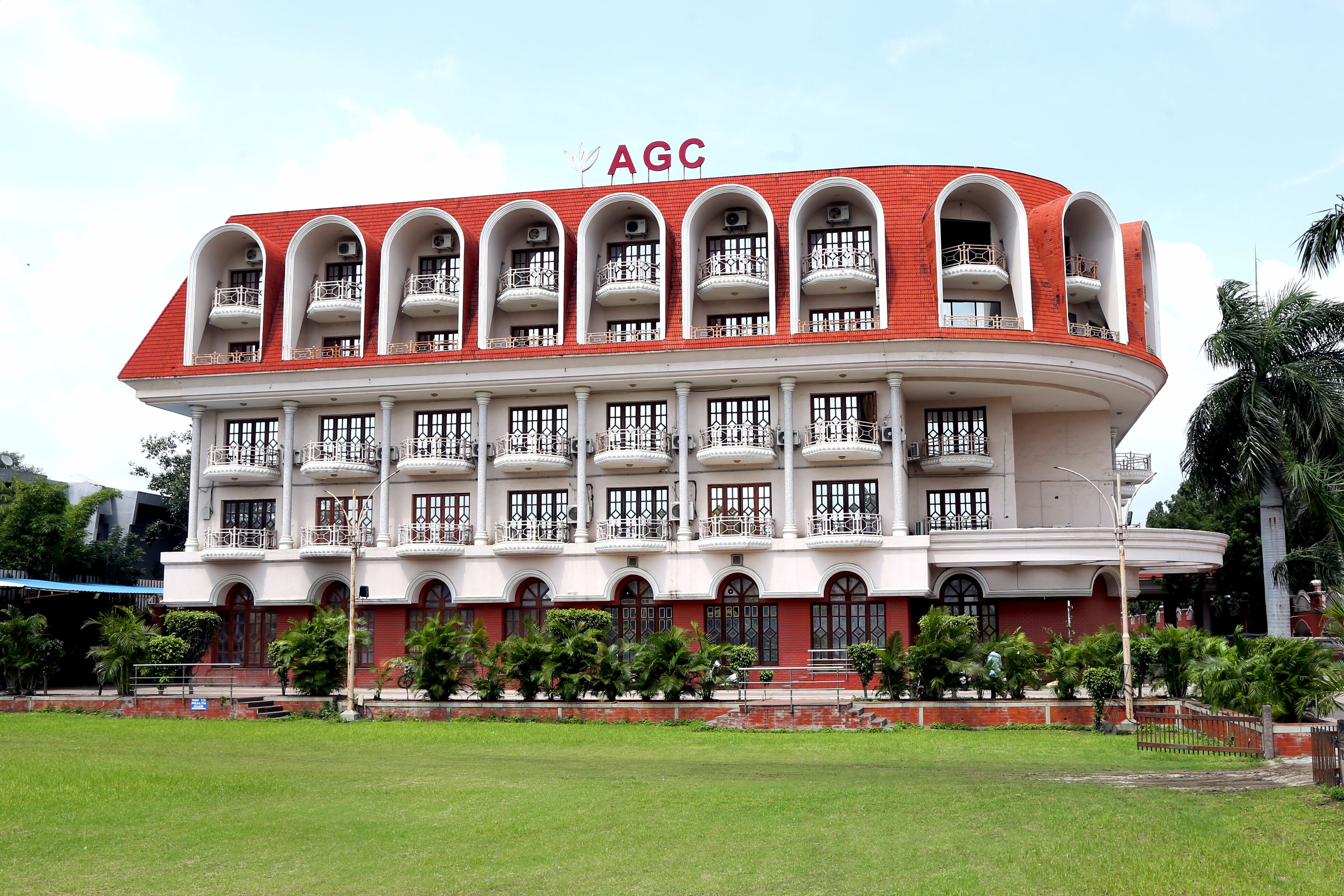 A large, multi-story building with balconies and a red roof, labeled "AGC".