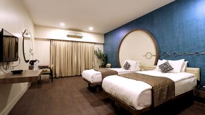 Habitación de hotel con dos camas, un escritorio, un televisor y un espejo grande.