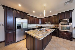 Une cuisine moderne avec des meubles en bois foncé, des appareils électroménagers en acier inoxydable et un plan de travail en granit.
