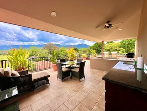 Un balcon avec une table et des chaises, un évier et une vue sur les montagnes.
