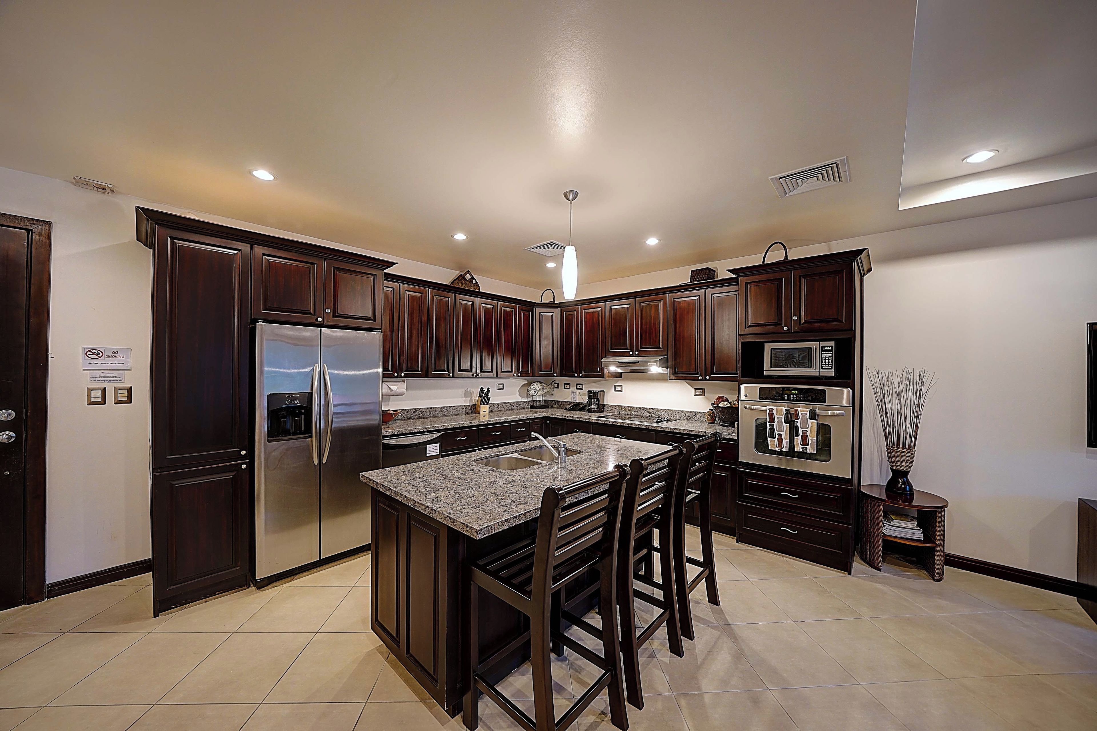 A modern kitchen with dark wood cabinets, stainless steel appliances, and a granite countertop.