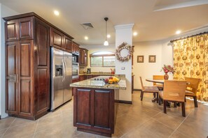 Una cocina con armarios de madera oscura, un refrigerador de acero inoxidable y una encimera de granito.