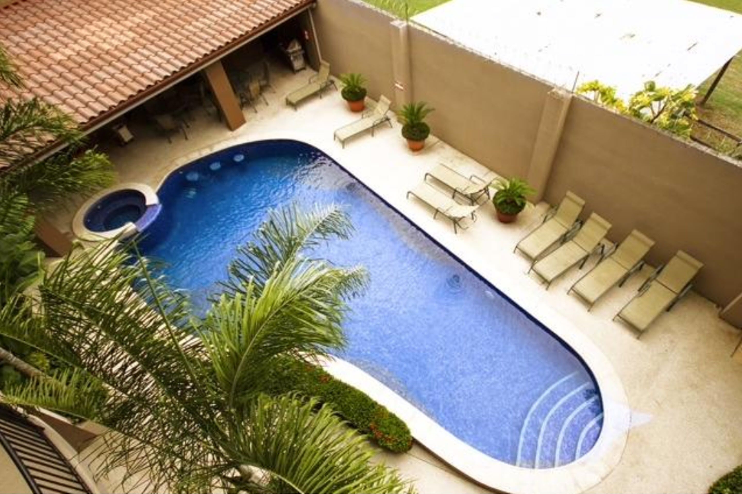 A swimming pool with lounge chairs and potted plants.