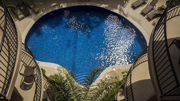 Una piscina circular amb un centre blau translúcid, envoltada per una paret baixa i una escala que hi baixa.