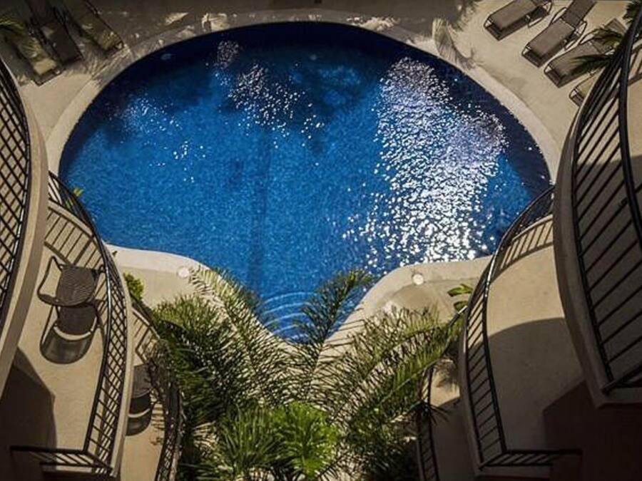 A circular pool with a clear blue center surrounded by a low wall and a staircase leading down.