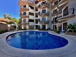 A swimming pool surrounded by a multi-story building with balconies.