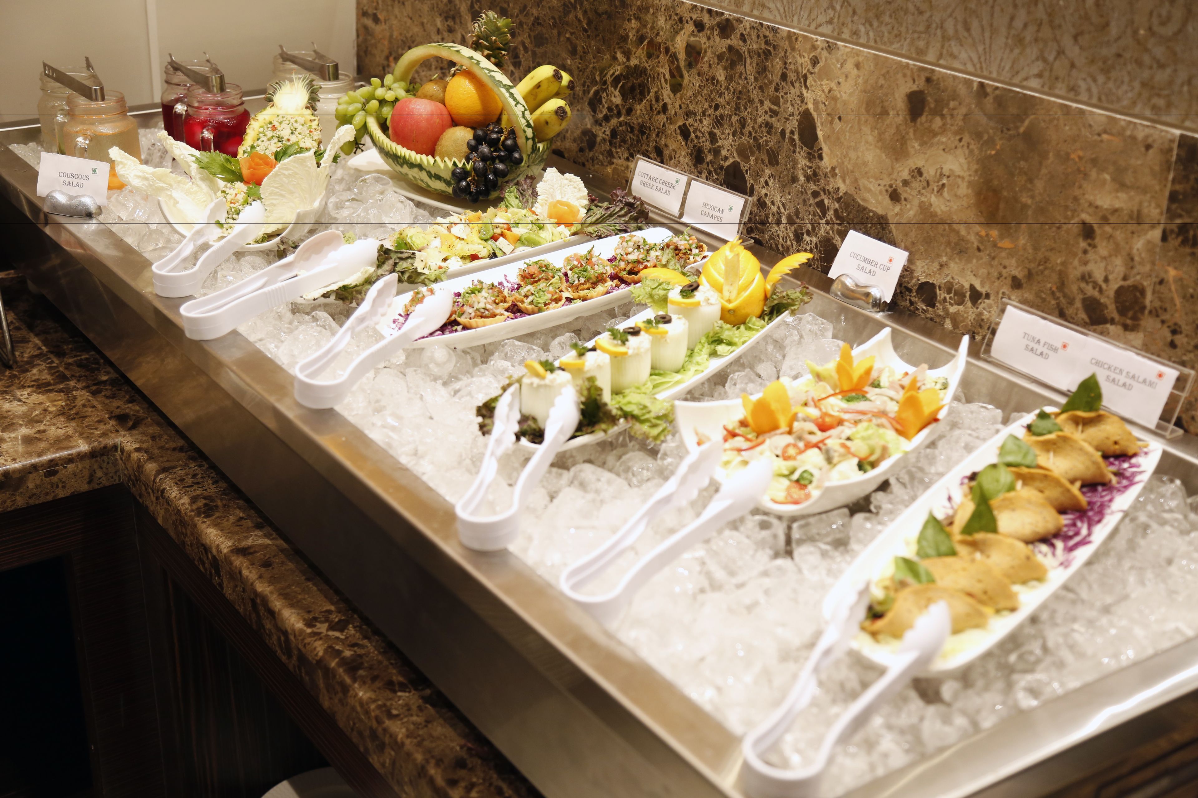 A buffet with various dishes and a fruit bowl.