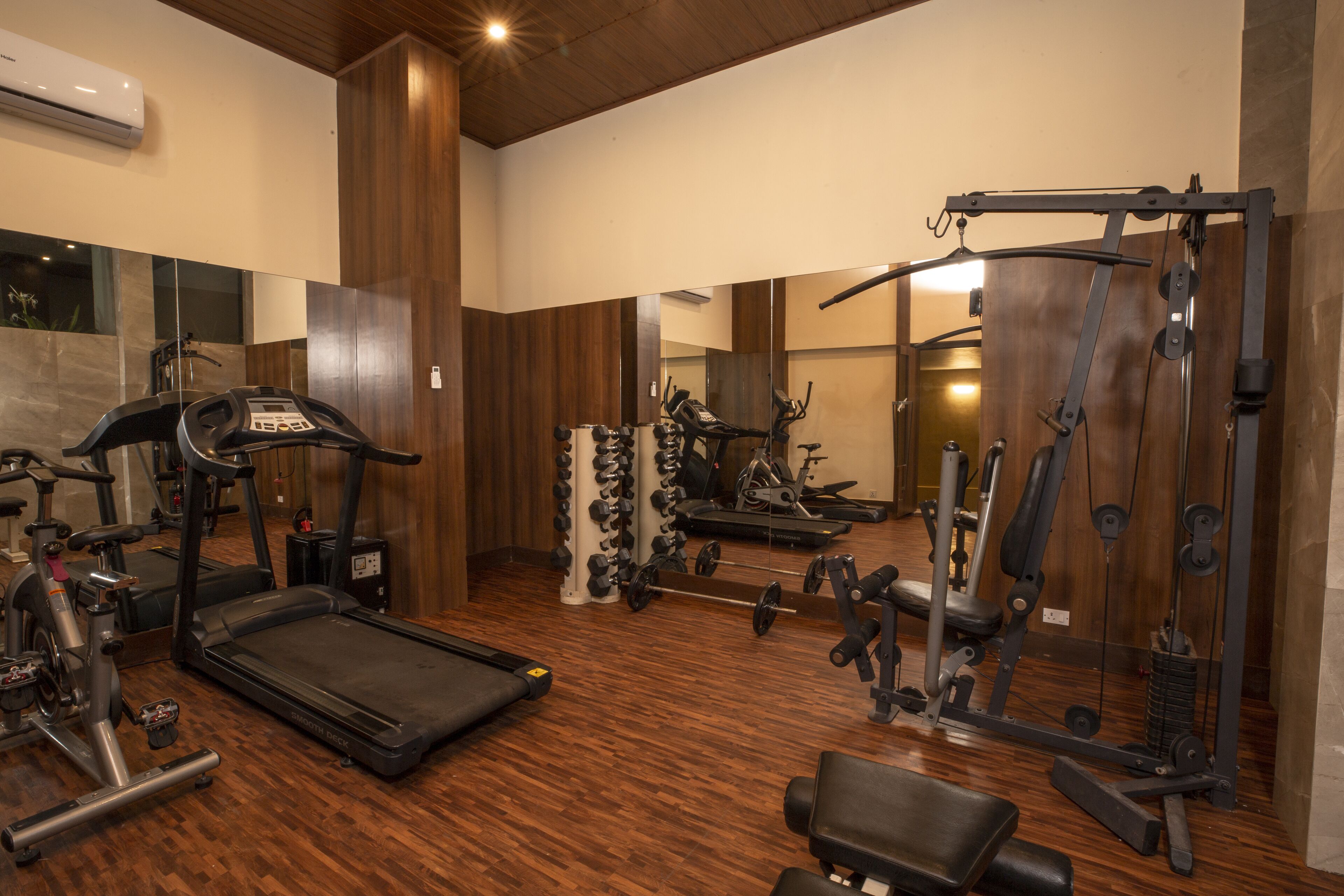 Ein Fitnessstudio mit Laufbändern, Kraftgeräten und Kurzhanteln.
