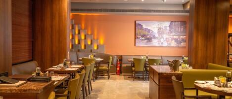 A restaurant with booths and tables, a fire extinguisher, and a cityscape painting on the wall.