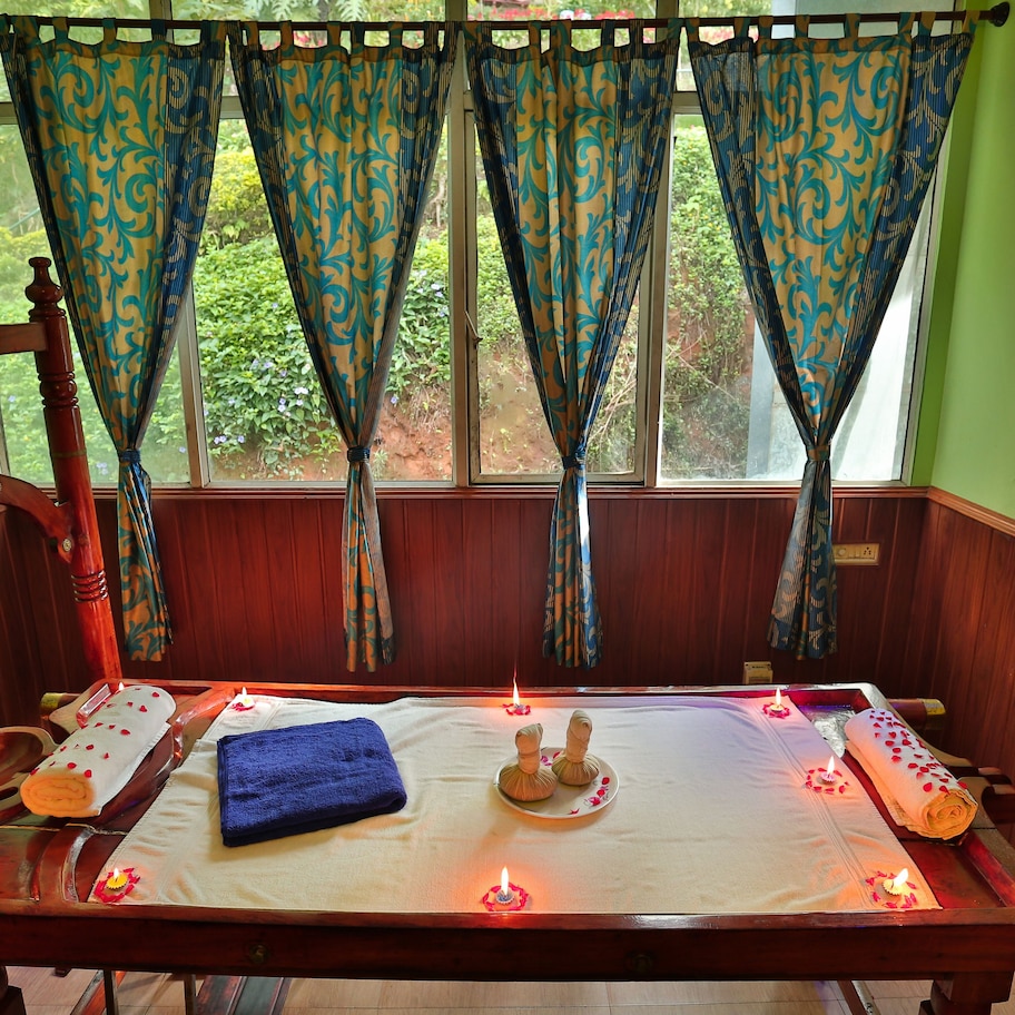A wooden massage table with candles, a blue towel, and a wooden headrest.