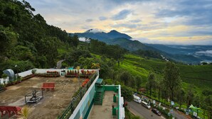 Un hotel con terraza que da a verdes colinas y una montaña.