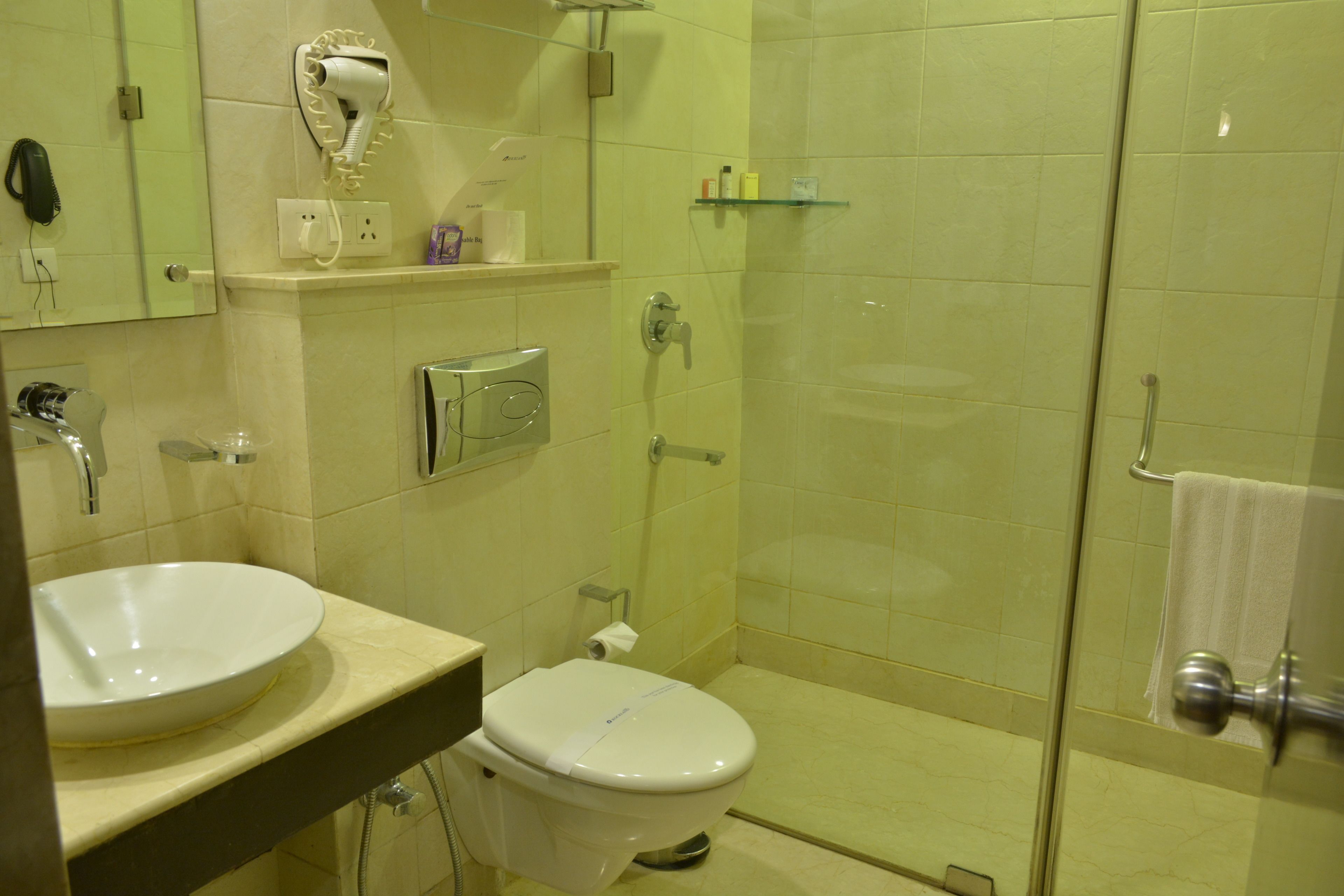 Baño con lavamanos, inodoro y cabina de ducha con mampara de vidrio.
